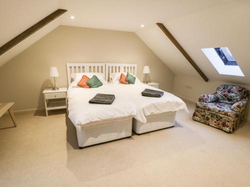 a bedroom with a large white bed and a chair at The Bothy, 21 West Street in Malton