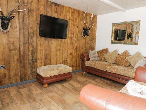 een woonkamer met een bank en een tv aan de muur bij Foxley Wood Cottage in Horsham Saint Faith