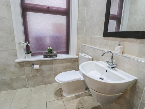 a bathroom with a sink and a toilet and a window at Flat 4 in Whitby