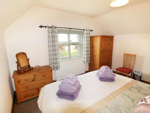 a bedroom with a bed with purple towels on it at Chippers Cottage in Woodhall Spa