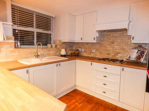 een witte keuken met witte kasten en een wastafel bij Edendale in Longframlington