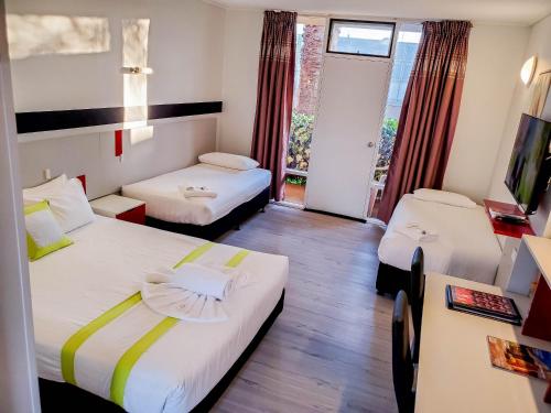 ein Hotelzimmer mit 2 Betten und einem Fenster in der Unterkunft Sandors Motor Inn in Mildura