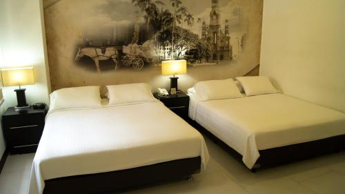 two beds in a hotel room with two lamps at Aw Hotel Puerta de San Antonio in Cali