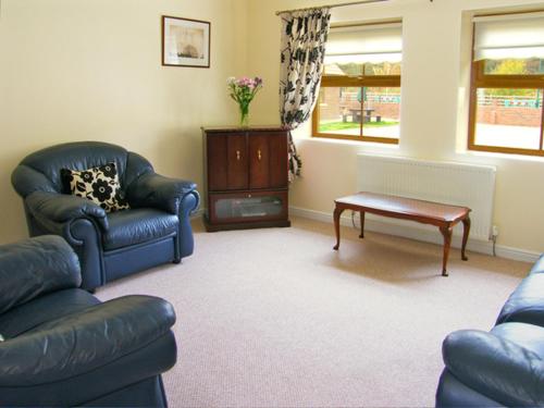 een woonkamer met 2 stoelen en een salontafel bij Drummer Cottage in Loftus