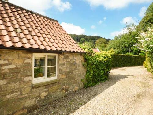 a stone house with a window and a hedge at Beckside in Lastingham