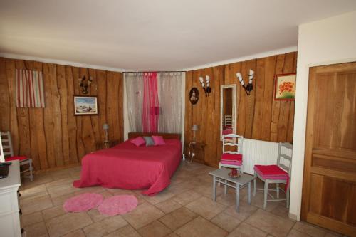1 dormitorio con cama roja y paredes de madera en Lou Cigalon, en Cabrières-dʼAvignon