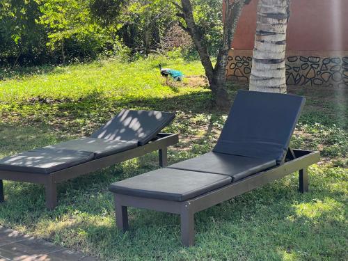 a bench and a chair sitting in the grass at Yala Peace Cottages in Tissamaharama