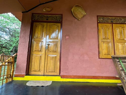a pink house with two wooden doors on it at Yala Peace Cottages in Tissamaharama
