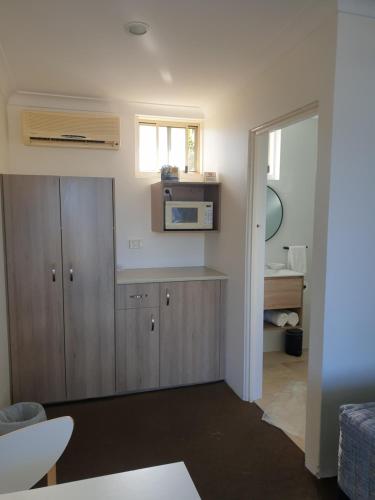 a kitchen with a cupboard and a sink in a room at Sandpiper Motel Ulladulla in Ulladulla