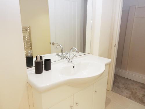 ein Badezimmer mit einem weißen Waschbecken und einem Spiegel in der Unterkunft Woodlands Farm in Ashbourne