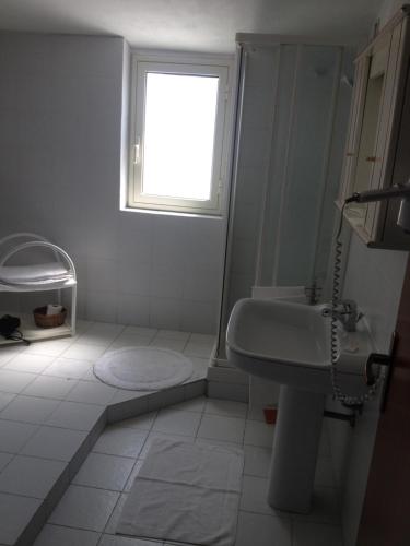 een witte badkamer met een wastafel en een raam bij Hotel Mareblu in Amantea