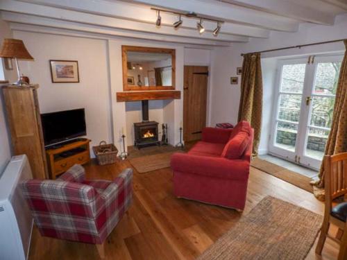 sala de estar con sofá rojo y chimenea en Brig End en Langthwaite