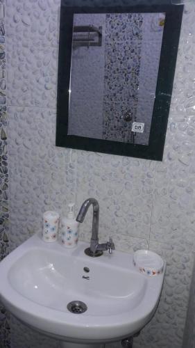 a bathroom sink with two cups and a mirror at Hotel Kanha Inn in Lucknow