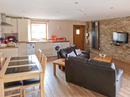 a living room with a couch and a table and a kitchen at Cooper Cottage in Potto