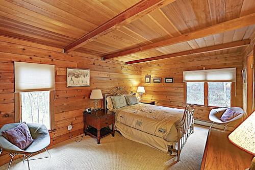 スノーマス・ビレッジにあるWood Road Houseの木製の壁のベッドルーム1室、ベッド1台、椅子2脚が備わります。