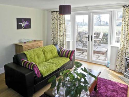 a living room with a green couch and a table at Grove Cottage in Malton