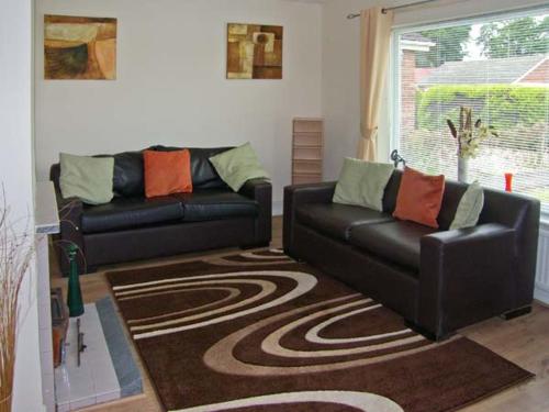 un soggiorno con 2 divani in pelle e un tappeto di Sunnyside Cottage a Skegness