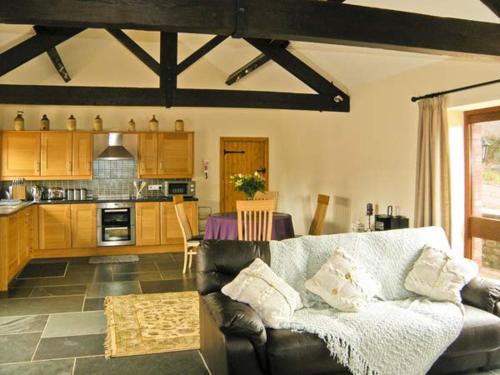 a living room with a couch and a kitchen at The Byre in Abergavenny