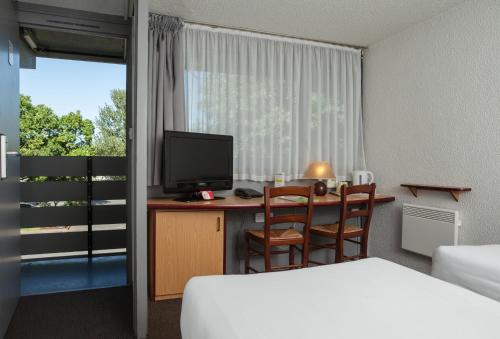 a hotel room with a desk with a television and a bed at Campanile Hotel - Basildon - East of London in Basildon