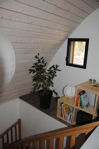 a staircase with a book shelf and a potted plant at Gîte Auberoques Aveyron- maison indépendante- classée 3 étoiles in Les Fonds