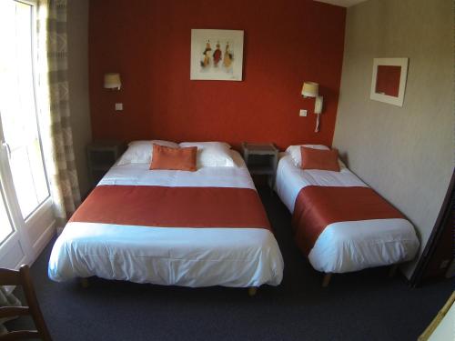 two beds in a hotel room with red walls at Hôtel des Vignes - Juliénas in Juliénas