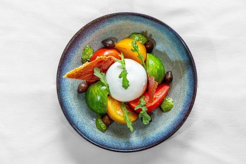 a blue plate of food with vegetables on a table at Hôtel Restaurant du Château de la Tour in Béguey