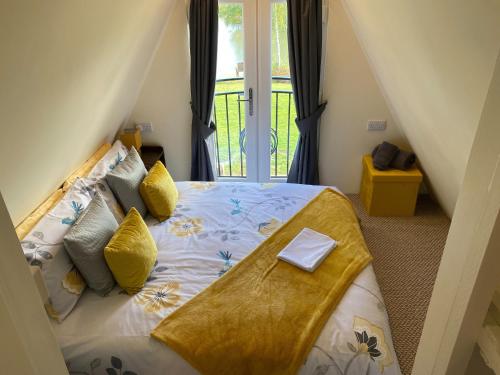 a bedroom with a bed with yellow pillows at Widgeon Bespoke Cabin is lakeside with Private fishing peg, hot tub situated at Tattershall Lakes Country Park in Tattershall