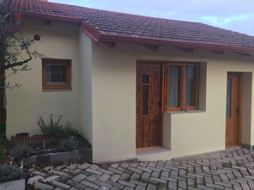 a small white house with a wooden door at Malé útulné studio s koupelnou a kuchyňkou in Svinařov