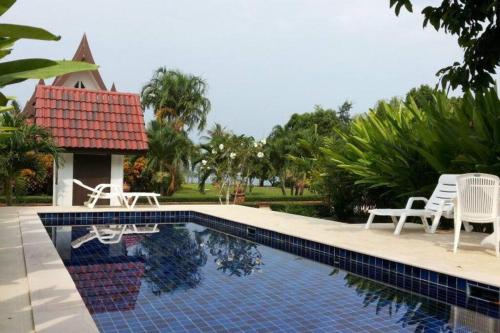 ein Swimmingpool mit zwei Stühlen und einem Haus in der Unterkunft Seabreeze Cottage in Ko Chang