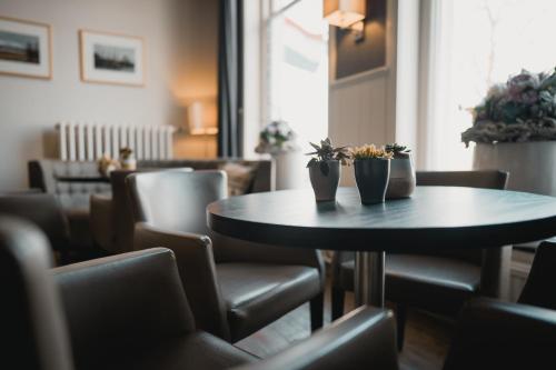 a table with two plants on it in a room with chairs at Hotel van Dijk in Kampen