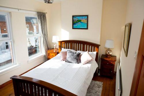 a bedroom with a bed with white sheets and pillows at Cheerful 2 bedroom house in the heart of Belfast in Belfast