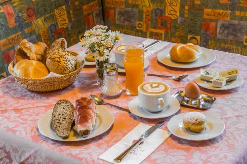 - une table avec des assiettes de produits pour le petit-déjeuner et du jus d'orange dans l'établissement Garni Baita, à San Cassiano