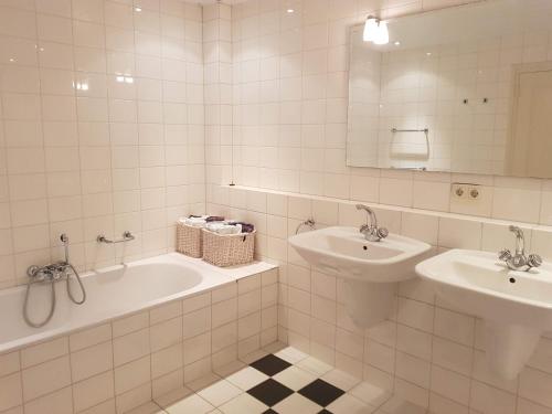 een witte badkamer met een bad en een wastafel bij Vakantiewoning Osebos in Gulpen