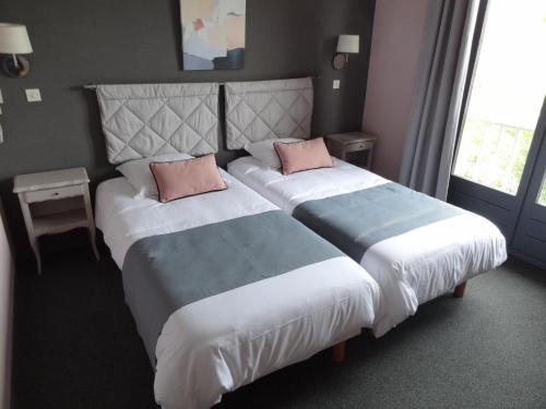 a hotel room with two beds with pink pillows at Hôtel des Vignes - Juliénas in Juliénas