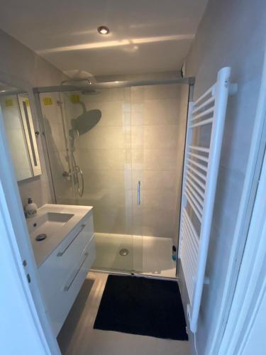 uma casa de banho branca com um chuveiro e um lavatório. em Frejus Plage Acapulco em Fréjus