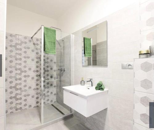 a white bathroom with a sink and a shower at Dagmar Apartment in Bratislava
