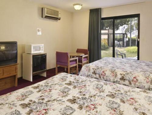 a hotel room with two beds and a television at Travelodge by Wyndham Turlock in Turlock