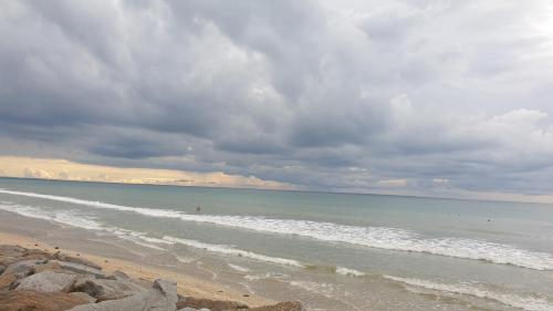 a beach with a cloudy sky and the ocean at Sylvie propriétaire du mobil-home in Saint-Pair-sur-Mer