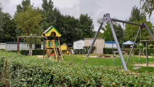a playground with two swings and a slide at Sylvie propriétaire du mobil-home in Saint-Pair-sur-Mer