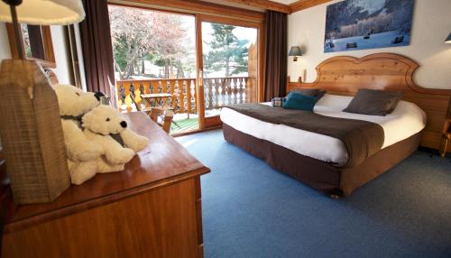 two teddy bears sitting on a dresser in a bedroom at Hôtel Serre Palas in Les Deux Alpes