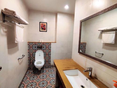 a bathroom with a toilet and a sink and a mirror at The Angel Hotel & Suites near Medanta in Gurgaon