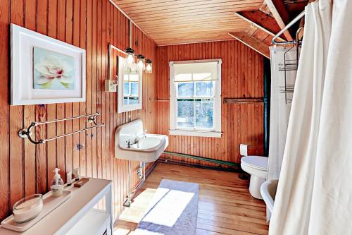 ein Badezimmer mit Holzwänden, einem Waschbecken und einem WC in der Unterkunft Green Gables Cottage in Friendship
