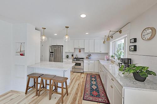 a white kitchen with a counter and stools in it at Newcastle Lake House in Newcastle
