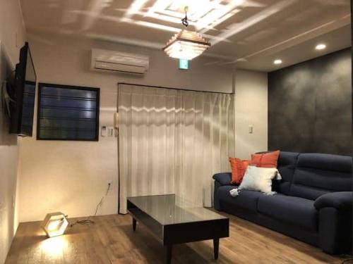 a living room with a blue couch and a table at ゲストハウス扇 in Takamatsu