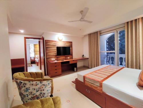 a bedroom with a bed and a desk and a television at The Angel Hotel & Suites near Medanta in Gurgaon