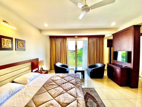 多納保拉的住宿－Kamat's Hilltop Leisure，一间卧室配有一张床、两把椅子和电视