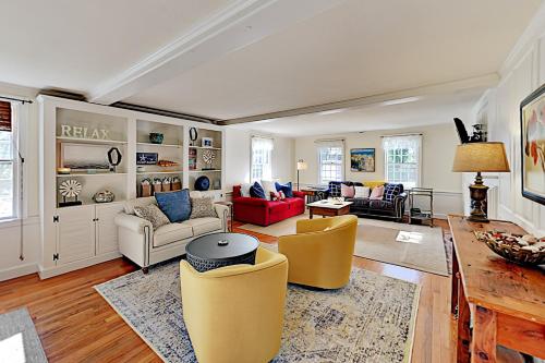a living room with yellow chairs and a red couch at Pleasant Bay Retreat in Orleans