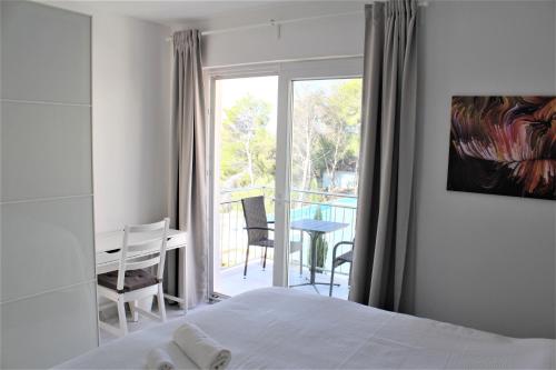 a bedroom with a bed and a table and a balcony at Villa Lovisa - 4 star villa with pool and amazing sea view in Milna