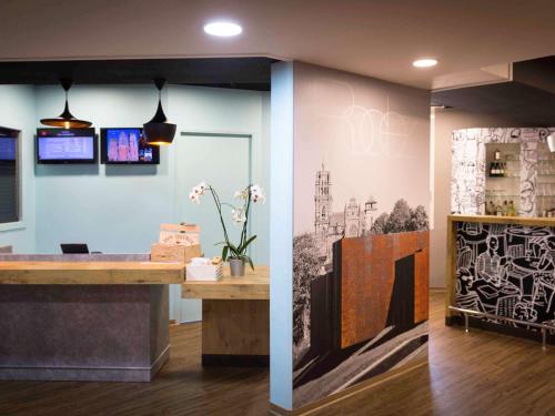a lobby with a reception desk and a painting on the wall at ibis Rodez Centre in Rodez