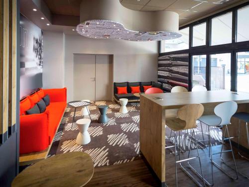 - un salon avec des chaises orange et une table dans l'établissement ibis Rodez Centre, à Rodez